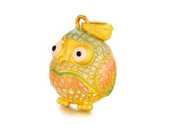 May include: A gold-colored owl pendant with a textured surface. The owl has large, round eyes and a small loop at the top for a chain. The owl's body is decorated with orange, green, and yellow accents.