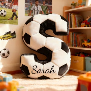 Cojín personalizado con nombre y letras de balón de fútbol. Ideal para amantes del fútbol y aficionados al Mundial 2026.