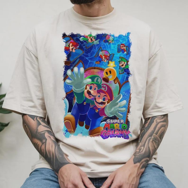 Puede incluir: Camiseta color crema con un gr&aacute;fico vibrante del videojuego Super Mario Galaxy. El dise&ntilde;o muestra a Mario y Luigi con un fondo c&oacute;smico y el logotipo del juego. La camiseta tiene un ajuste c&oacute;modo y holgado.