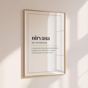 May include: A framed print with the definition of "nirvana." The word "nirvana" is in a bold, black font, with the pronunciation and definition below. The frame is gold, and the background is a light beige color.
