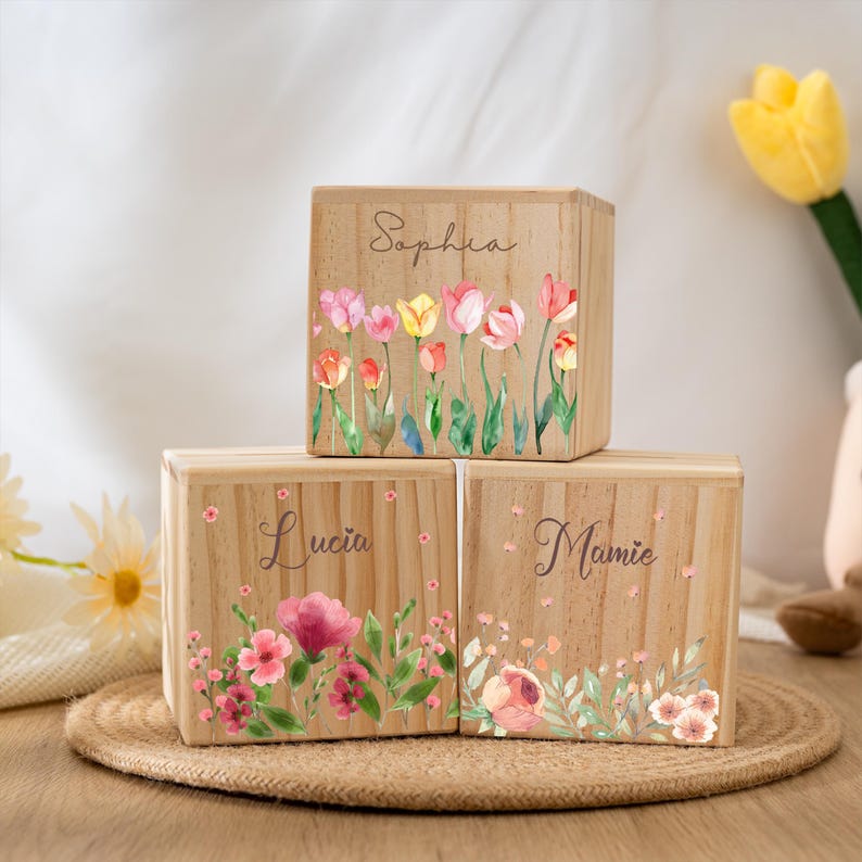 May include: Three wooden boxes with floral designs and personalized names: Sophia, Lucia, and Mamie. The boxes are stacked on top of each other and have a light wood finish.