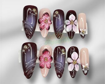 Può includere: Un set di dieci unghie finte a forma di mandorla. Le unghie presentano una finitura lucida nei toni del bordeaux, nude e viola. Alcune unghie sono decorate con disegni floreali 3D rosa e bianchi, altre hanno accenti dorati.