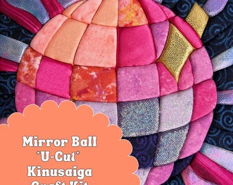 May include: A Kinusaiga craft kit featuring a quilted fabric mirror ball design in shades of pink, orange, and gold, surrounded by dark blue patterned fabric. The text Mirror Ball *U-Cut* Kinusaiga Craft Kit is printed on a scalloped orange overlay.