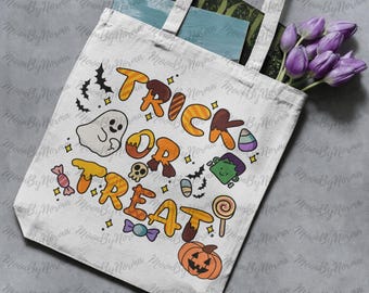 May include: A white tote bag with the words "TRICK OR TREAT" in orange and brown letters. The design includes Halloween-themed illustrations such as a ghost, candy, a pumpkin, and a Frankenstein monster. The bag has white handles and is filled with purple flowers.