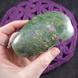 May include: A green and pink gemstone with gold flecks. The stone is smooth and polished, and has a unique, organic shape.