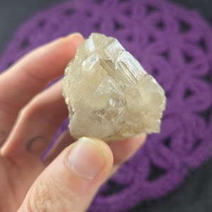 May include: A cluster of clear, translucent, and slightly yellow crystals with a rough, natural texture.
