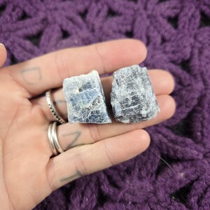 May include: Two rough, gray-blue kyanite crystals with a slightly iridescent sheen.