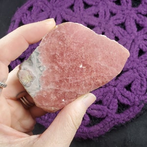 May include: A pink and white crystal with a rough, natural texture. The crystal is translucent and has a light pink hue. It is a beautiful example of a natural crystal.