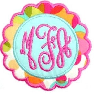 May include: A circular embroidered patch with a light blue central area displaying the pink monogram "MSF". The patch has a scalloped edge with a colourful pattern of pink, orange, yellow, and green polka dots. The outer edge is pink.
