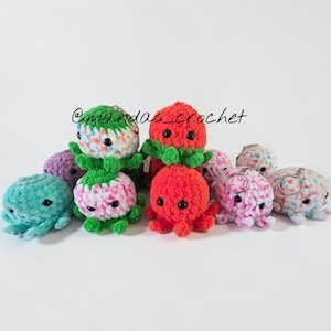 May include: A collection of colorful, crocheted octopus plushies in various colors, including teal, purple, red, pink, and green. Some have keychains attached. The text "@mandas_crochet" is visible.