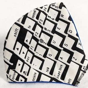 May include: A white and black fabric face mask with a keyboard design. The mask has a blue trim around the edges. The keys on the keyboard include letters, numbers, and symbols. The text on the keys includes "shift", "alt", "option", "esc", "F1", "F2", "F3", "F4", "tab", "caps lock", and "delete".