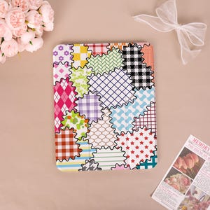 May include: A rectangular tablet case featuring a colorful patchwork design of various patterns including gingham, argyle, polka dots, stripes, and stars in shades of pink, blue, green, yellow, red, black, and white with scalloped edges.