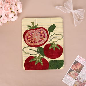 May include: A tablet case featuring a tomato design. The tomatoes are red with green plaid accents and leaves, set against a cream-colored background with vertical lines. The design has a patchwork style.