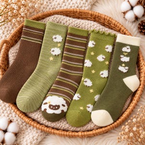 May include: Five pairs of crew socks in shades of green and brown. Designs include solid ribbed brown with stripes, light green with small sheep, brown with horizontal stripes and a large sheep, olive green with sheep, and dark green with sheep.