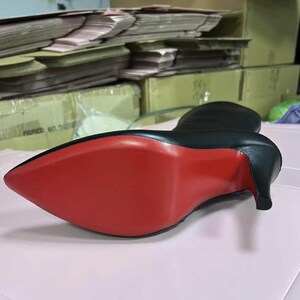 Puede incluir: Bota negra de cuero de tac&oacute;n alto con punta y suela roja. El tac&oacute;n es de estilo stiletto. La bota est&aacute; sobre una superficie rosa.