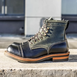 Puede incluir: Bota de trabajo de cuero negro y verde con puntera y cordones marrones. La bota presenta un tacón apilado y una construcción Goodyear. La suela está hecha de un material duradero y la bota tiene un diseño clásico y robusto.