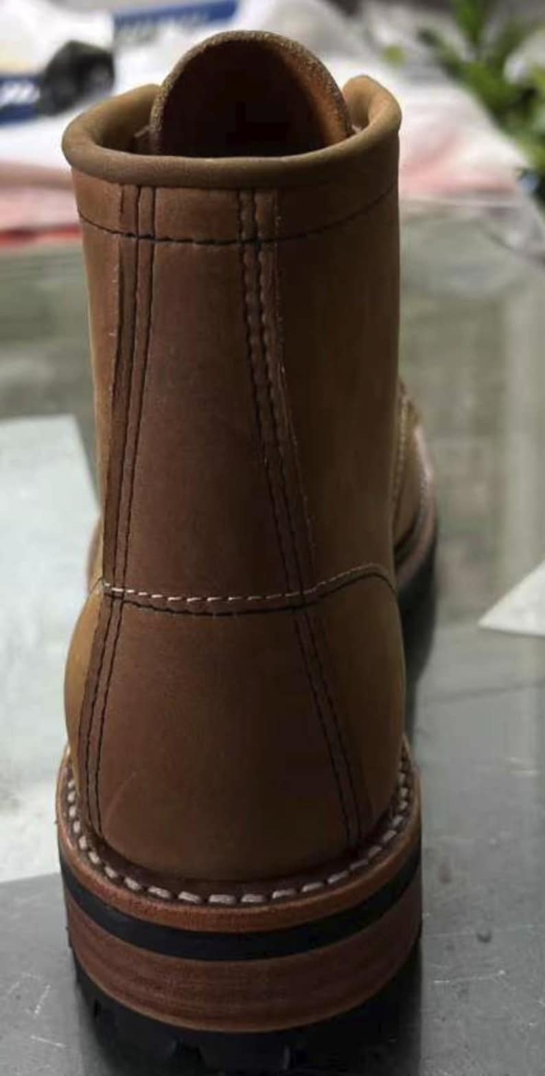 May include: A brown leather work boot with a rounded toe and a sturdy sole. The boot features visible stitching and a padded collar. The heel is approximately 1.5 inches high. The boot is designed for durability and rugged use.