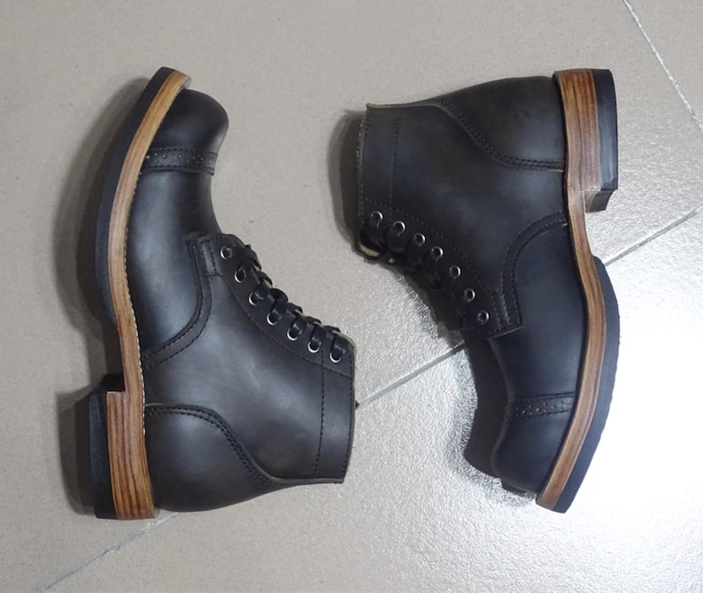 May include: A pair of black leather lace-up boots with brown leather soles. The boots have a rugged look and are made of high-quality materials.