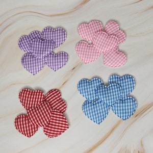 以下が含まれることがあります： 赤、青、紫のギンガムチェックのハート型の生地パッチの詰め合わせ。