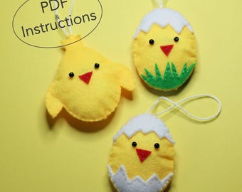 May include: Three felt Easter chick ornaments, two are chicks in eggshells and one is a chick with wings. The chicks are yellow with black eyes, red beaks, and white accents. The eggshells are white with a scalloped edge. The ornaments have white string loops for hanging.