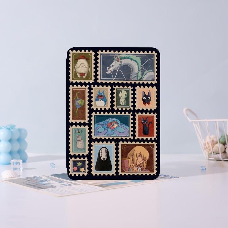 Puede incluir: Una funda rectangular negra con un collage de coloridos dise&ntilde;os de sellos postales. Los sellos representan varios personajes animados, incluyendo un drag&oacute;n, un gato y otras figuras caprichosas. La funda est&aacute; sobre un fondo azul claro.