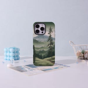 May include: A phone case featuring a landscape painting of a mountain range and evergreen trees. The case is green and has a camera cutout. The design includes a path leading through a grassy area towards the mountains.