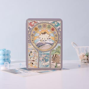 May include: A rectangular, lavender-colored box with a detailed, colorful illustration. The artwork features a central image of a flying bison over a mountain range, surrounded by stylized elements of nature and mythical creatures. The design is reminiscent of Art Nouveau.