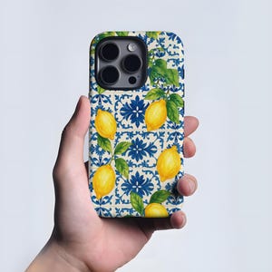 Op de afbeelding: Een telefoonhoesje met een citroen- en bladerenontwerp op een blauw en wit tegelpatroon. De hoes heeft een glanzende afwerking en een uitsparing voor de camera. Het ontwerp bevat gele citroenen en groene bladeren.