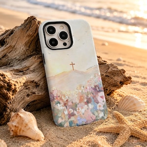 May include: A phone case featuring a painted landscape with a cross atop a hill, a field of colorful flowers in shades of pink, blue, and orange, and the text Matthew 6:25-34. The design has a soft, textured appearance with a black camera frame.