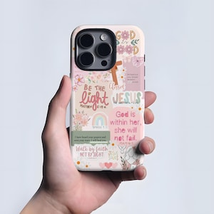 Puede incluir: Una funda de teléfono con un diseño floral y pastel. La funda presenta las palabras "Dios es", "Sé la luz" y "Jesús". Otros textos incluyen versículos bíblicos y frases como "Camina por fe". La funda tiene una combinación de colores rosa, blanco y beige.