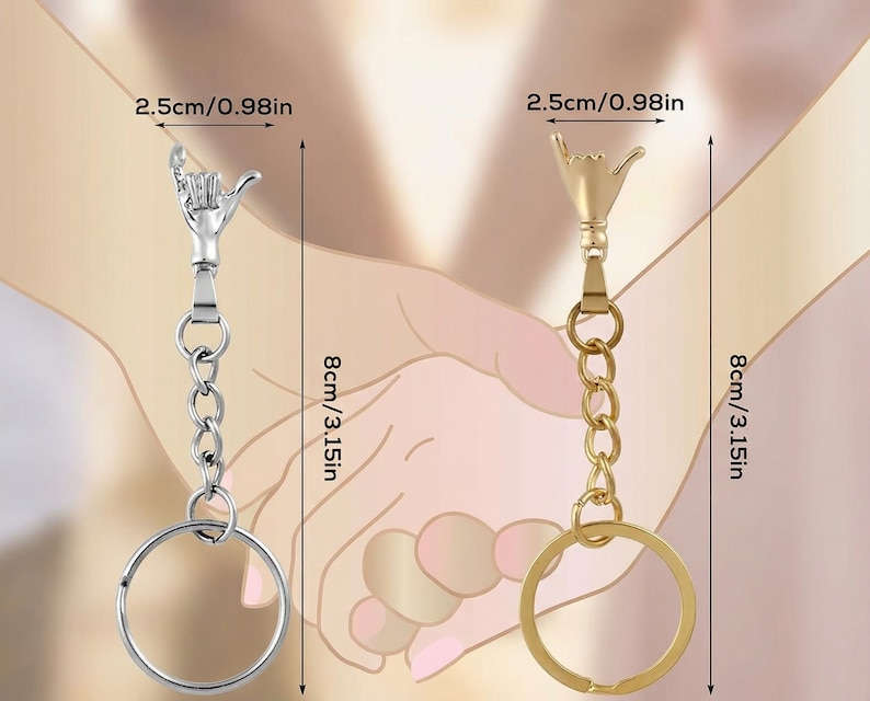 May include: Two keychains, each 8 inches (20 cm) long, featuring a hand gesture design. One keychain is silver-colored, the other gold-colored. Both have a chain and a round key ring. The hand gesture is 0.98 inches (2.5 cm) wide.