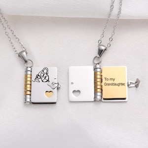 May include: Two silver-tone lockets with chains. One locket is open, revealing the inscription "To my Granddaughter." The other locket has a heart-shaped cutout. Both lockets have a gold-colored accent and a small clasp.
