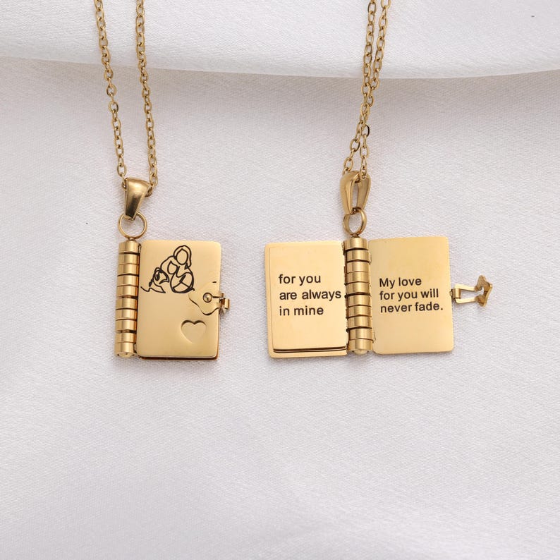 May include: Two gold-colored locket necklaces. One is closed, showing a butterfly design and a heart. The other is open, revealing the engraved text: "for you are always in mine" and "My love for you will never fade."
