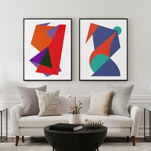 Peut inclure: Deux impressions d'art mural encadrées présentant des formes géométriques abstraites aux couleurs vives, notamment rouge, orange, violet, bleu et sarcelle sur fond blanc. L'impression de gauche montre des formes angulaires et celle de droite des courbes.