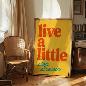 以下が含まれることがあります： オレンジとターコイズの文字で「live a little stop stressin」と書かれた黄色のポスターです。
