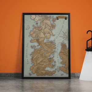Può includere: Mappa incorniciata di Westeros, raffigurante il continente immaginario con dettagli. La mappa è nei toni del marrone e beige, con una rosa dei venti ed etichette di testo. La cornice è nera.
