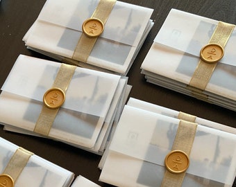 May include: Several white envelopes with gold ribbon and wax seals. Each seal has the initials "D & A" in gold lettering.