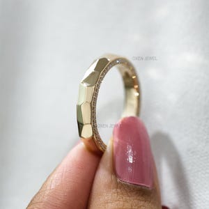 May include: A gold ring with a geometric design and small embedded stones. The ring is held by a person with a pink manicure. The brand name "OXEN JEWEL" is visible on the ring.