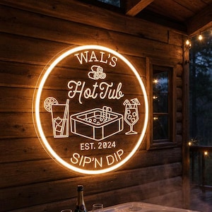 Könnte beinhalten: Ein Neonschild mit der Aufschrift "Wal's Hot Tub" mit dem Text "Sip 'N Dip" und dem Jahr "2024" ist an einer Holzhüttenwand angebracht. Der Whirlpool ist mit Wasser gefüllt, und ein Holztablett enthält Champagner und Gläser. Lichterketten und ein Waldhintergrund vervollständigen die Szene.