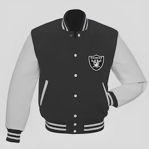 Puede incluir: Chaqueta universitaria negra y blanca con el logotipo de los Raiders en el pecho. La chaqueta presenta mangas blancas, cuerpo negro y detalles a rayas blancas en los puños, el cuello y el dobladillo. Una prenda de abrigo clásica de inspiración atlética.