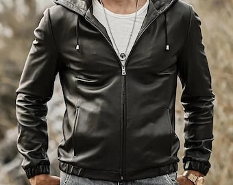 May include: A black leather jacket with a hood and a zipper closure. The jacket has a fitted silhouette and features a drawstring hood, side pockets, and ribbed cuffs. The model is wearing a white t-shirt and blue jeans.