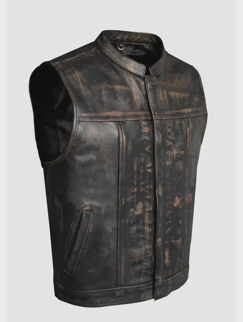 May include: A distressed black leather vest with a stand-up collar and a front zipper. The vest has a weathered appearance with brown accents and a single pocket on the front. The vest is sleeveless and has a classic biker style.