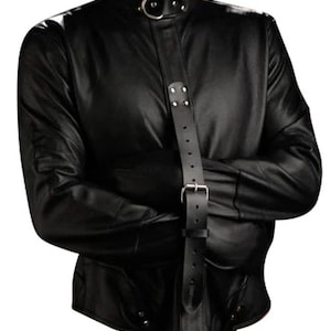 May include: Black leather jacket with a high collar and a vertical strap closure. The jacket features long sleeves and a fitted design. The collar has a metal ring detail. The strap has a metal buckle.