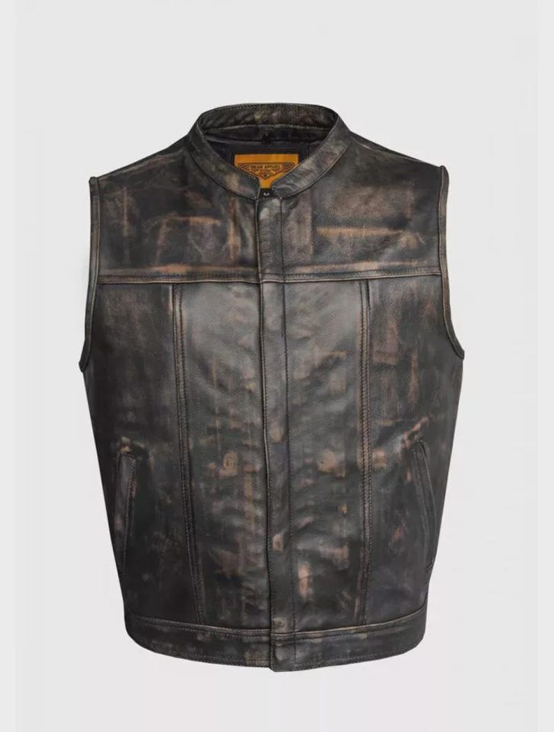 May include: A distressed black leather vest with a stand-up collar and a zip-up front. The vest has a weathered appearance with brown accents and two front pockets. A small tag is visible near the collar.