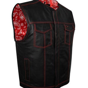 May include: Black leather vest with red stitching and a red paisley lining. The vest features two chest pockets and a classic biker style. The red stitching provides a striking contrast against the black leather.