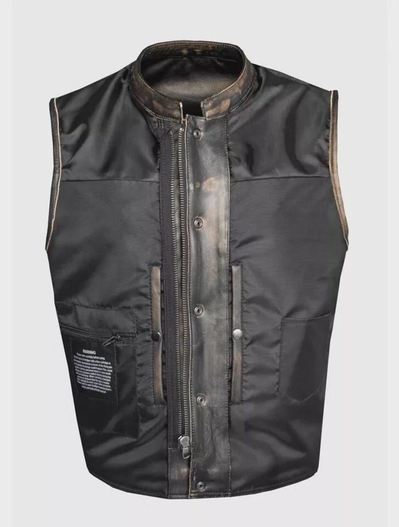 May include: Black vest with a stand-up collar and a front zipper. The vest has a leather-like appearance with a distressed finish and a quilted interior. Features include two front pockets and a small interior pocket.
