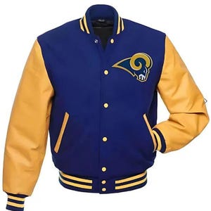Puede incluir: Chaqueta universitaria azul y dorada con el logotipo del equipo en el pecho. La chaqueta tiene mangas doradas, cuerpo azul y ribetes a rayas doradas y azules en los puños y la cintura. Tiene cierre de botones y dos bolsillos delanteros.
