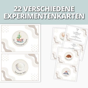 以下が含まれることがあります： 「22 VERSCHIEDENE EXPERIMENTENKARTEN」のテキストが入った実験カードのセット。カードにはヨット、米、風船、火山のイラストが描かれています。カードは白地で、ベージュとグレーの装飾要素があります。