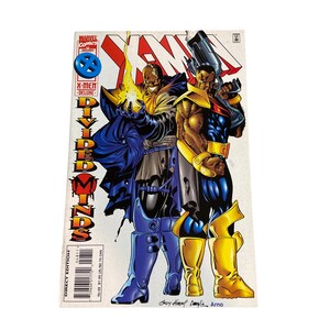 May include: X-Men comic book featuring two costumed characters. One character is in blue and gold, holding a weapon. The other character is in blue and gray, with a yellow energy blast. The comic has the text "X-Men Deluxe" and "Divided Minds".