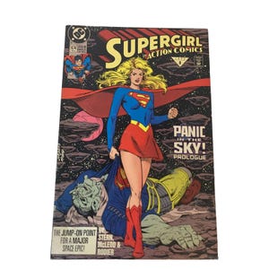 May include: A Supergirl comic book cover. The cover features Supergirl in a blue top, red skirt, and boots, with a red cape. The comic book title is "Supergirl in Action Comics" with the text "Panic in the Sky!" and "Prologue".